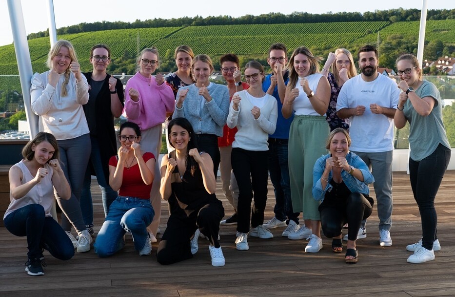Gruppe posiert für ein gemeinsames Foto auf der Terrasse mit Blick auf Weinberge.